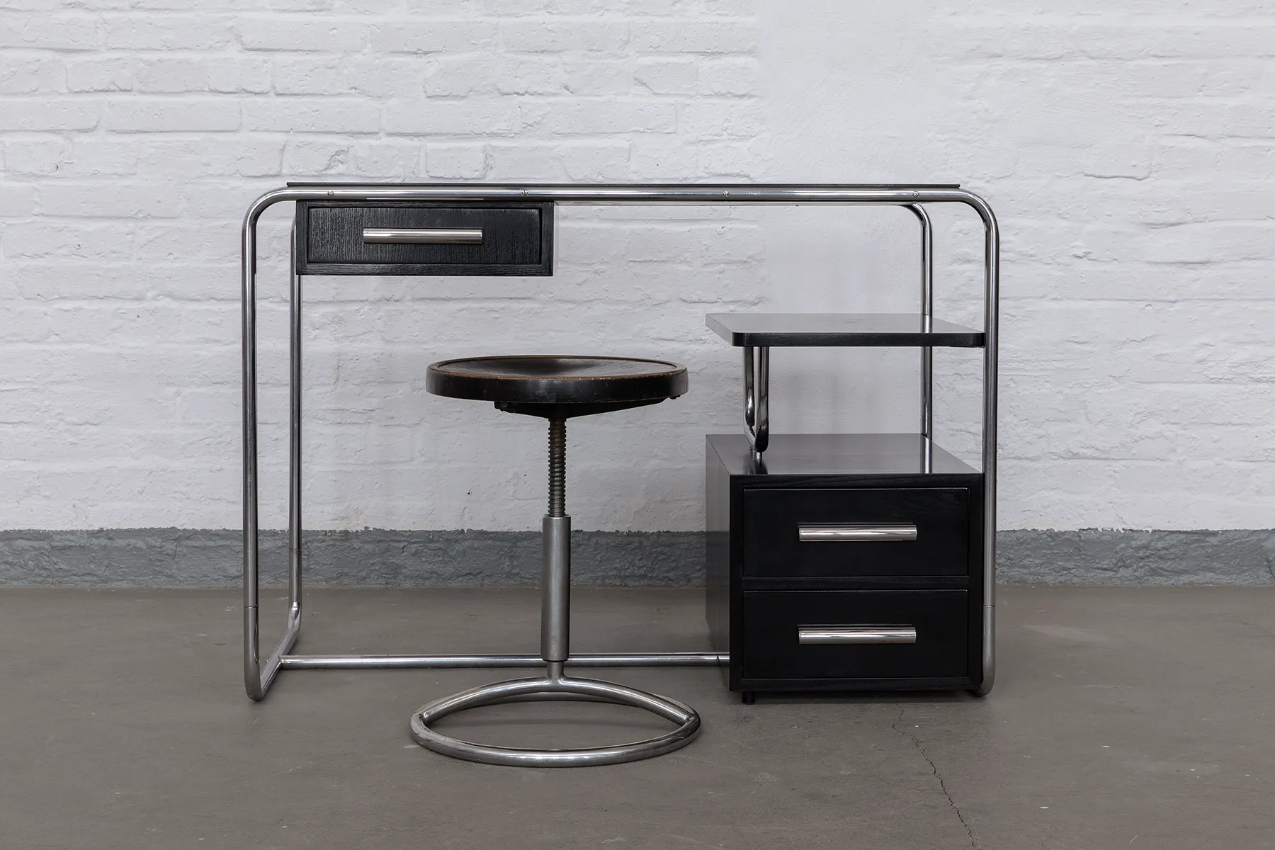 Original Bauhaus steel tube desk from the 1930s with polished steel tubing and black-stained panels. Compact, minimal design with integrated storage and restored craftsmanship. Available now on KaDeMo: www.kademo.store.