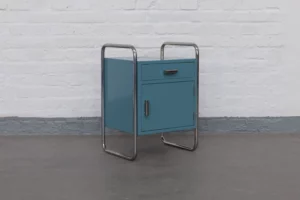 Thonet Bauhaus bedside table, circa 1930. Chromed tubular steel frame and lacquered wooden body in restored original petrol color. With characteristic Bauhaus cylindrical handles.
Available exclusively at KADEMO.store – specialists in authentic Bauhaus furniture and curated modern design classics.