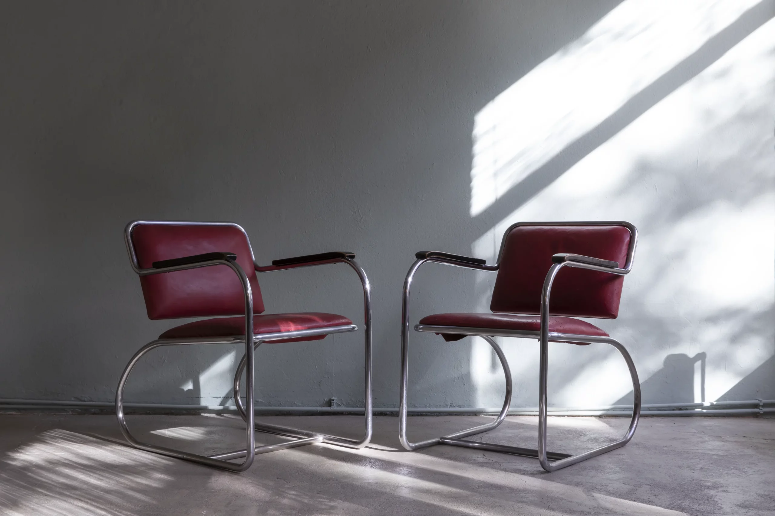 Original RS-series tubular steel cantilever chair by Heinz & Bodo Rasch for Alfons Mauser, 1930s, with oxblood-red upholstery and black-lacquered armrests.