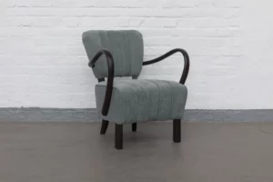 H-237 armchair by Jindřich Halabala in restored condition with curved dark wooden armrests and vertically structured upholstery, photographed in three-quarter view.