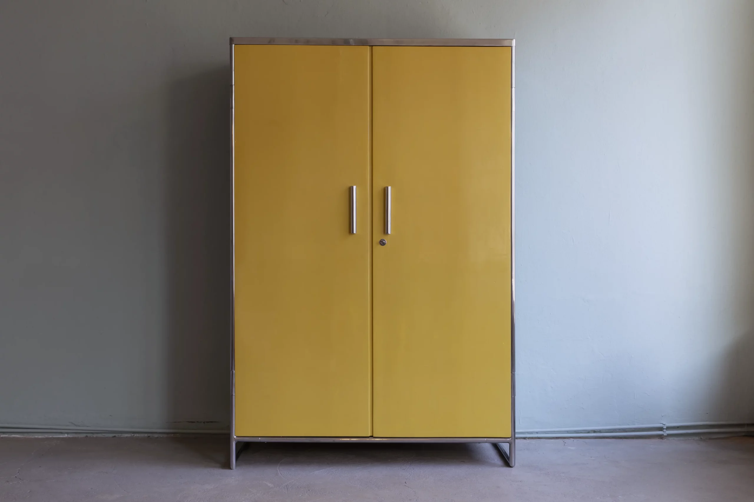 A highly expressive Bauhaus wardrobe from the early 1930s, designed by John Hagemann and produced under license by Hynek Gottwald, featuring yellow and blue painted surfaces and a tubular steel frame.