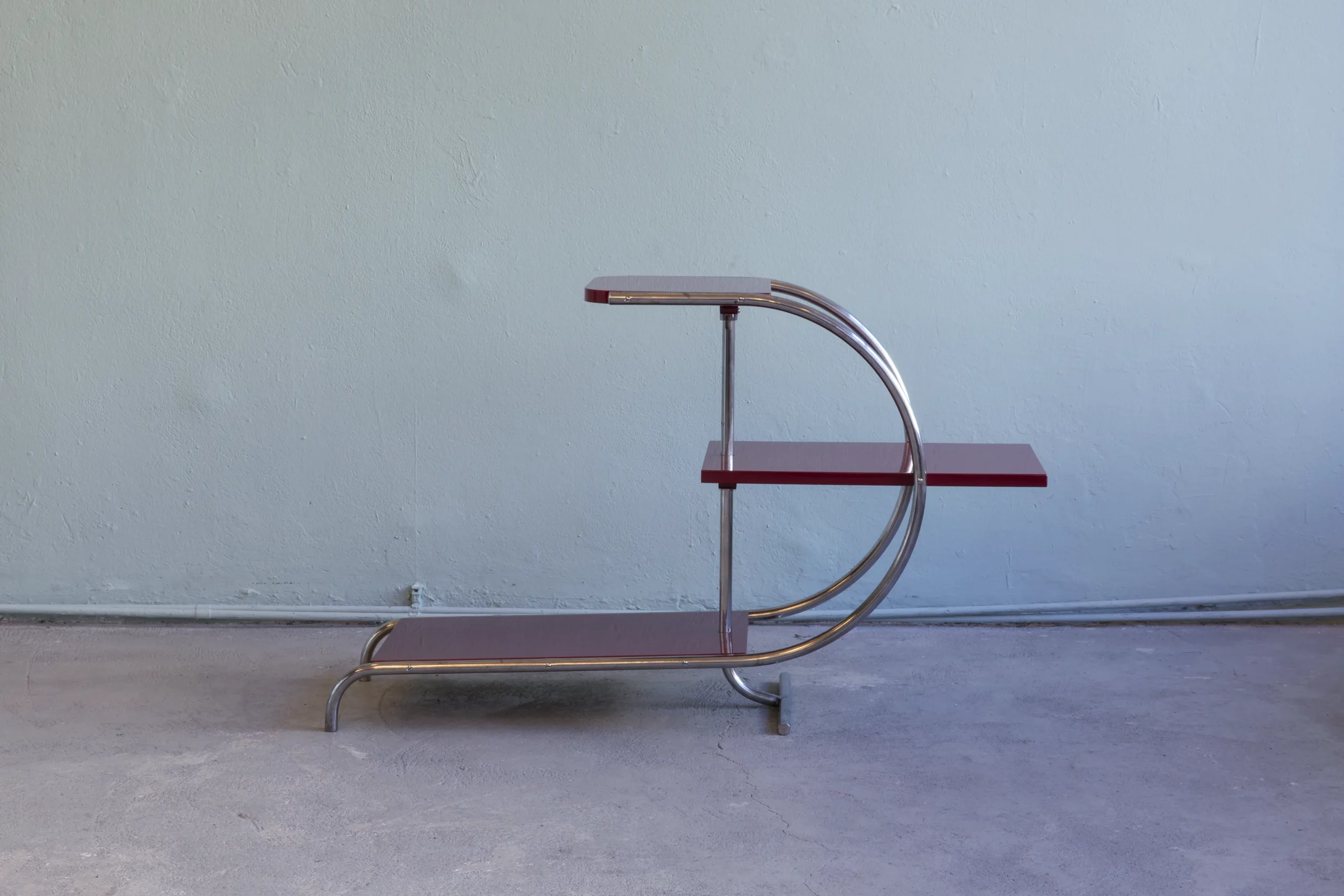 1930s étagère in the Streamline Moderne style, designed by Jindřich Halabala, tubular steel frame with red lacquered wooden shelves.