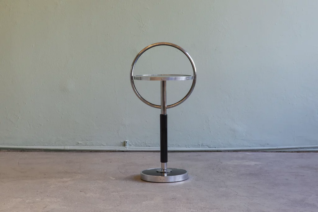 Small side table in the style of Classical Modernism featuring a circular tubular steel loop, black lacquered wooden surfaces and a metal profile surround. Handcrafted in the KADEMO workshop.